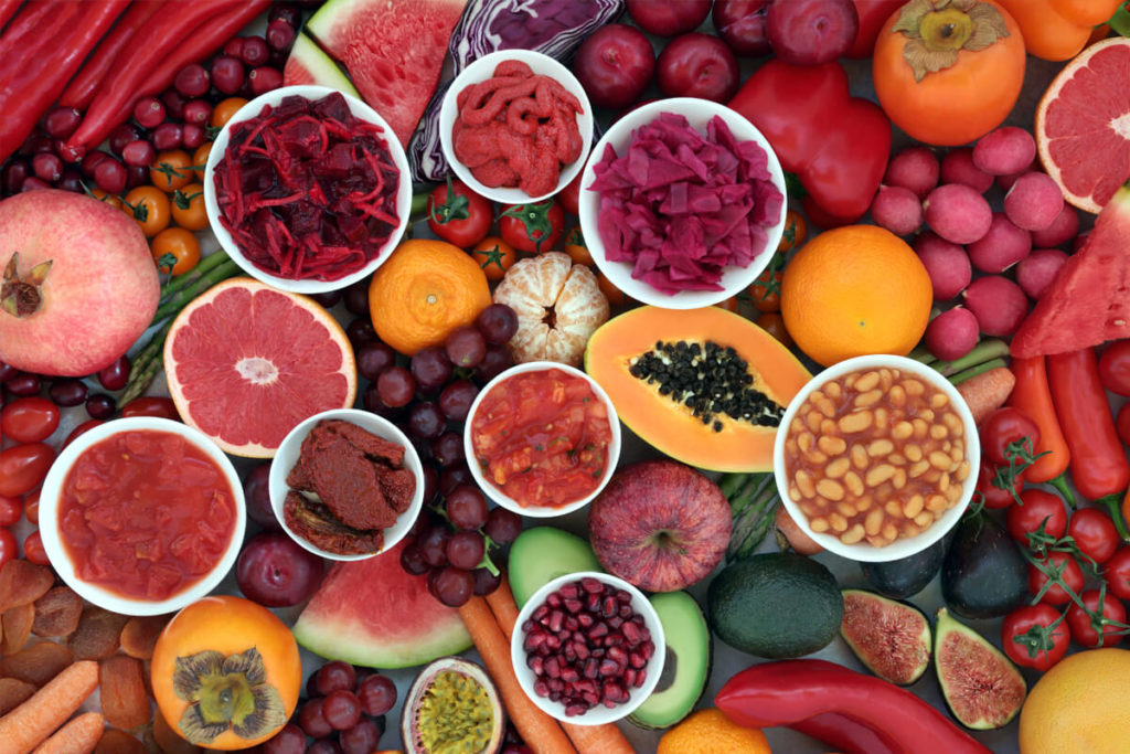 Many phytonutrient-rich fruits and vegetables laid out, including persimmons, watermelons, apples, avocadoes, cherries, figs, beetroot, and much more.