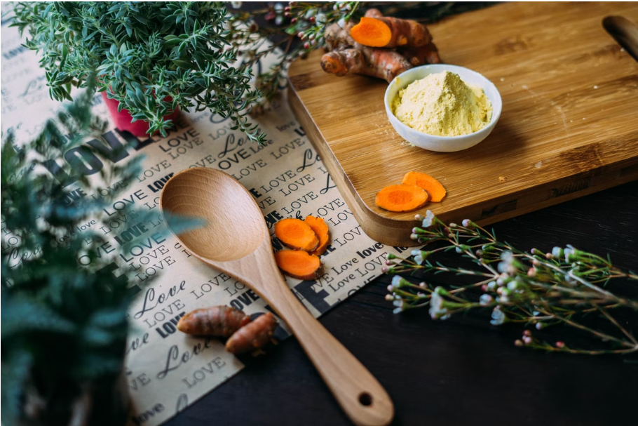 Many medicinal herbs spread on a table next to a wooden spoon and a small mortar