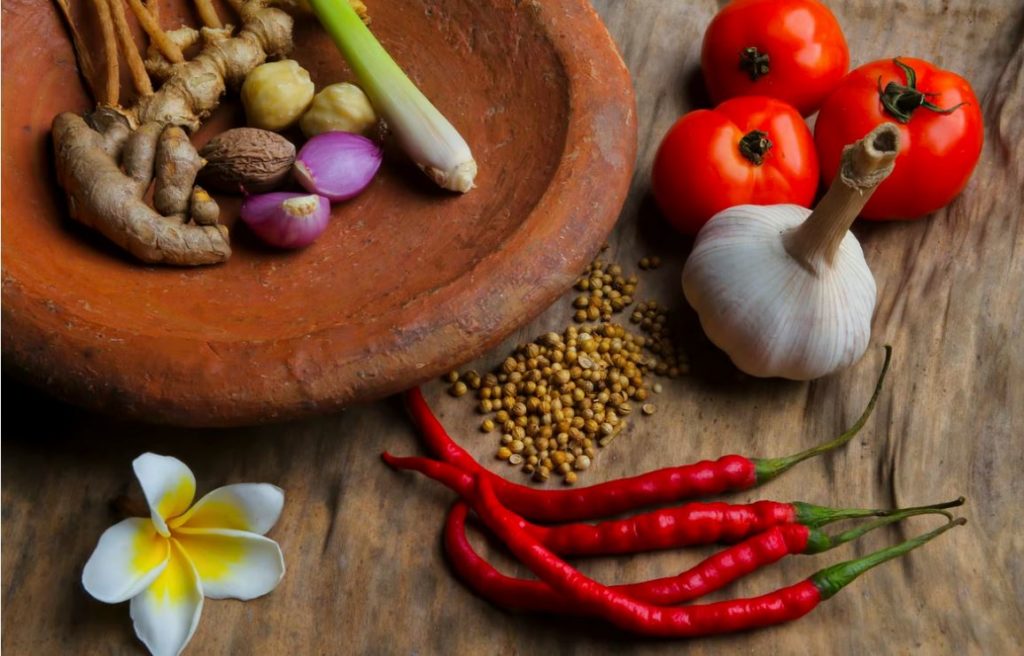 Various healthy herbs including turmeric root, ginger, garlic, and chili peppers